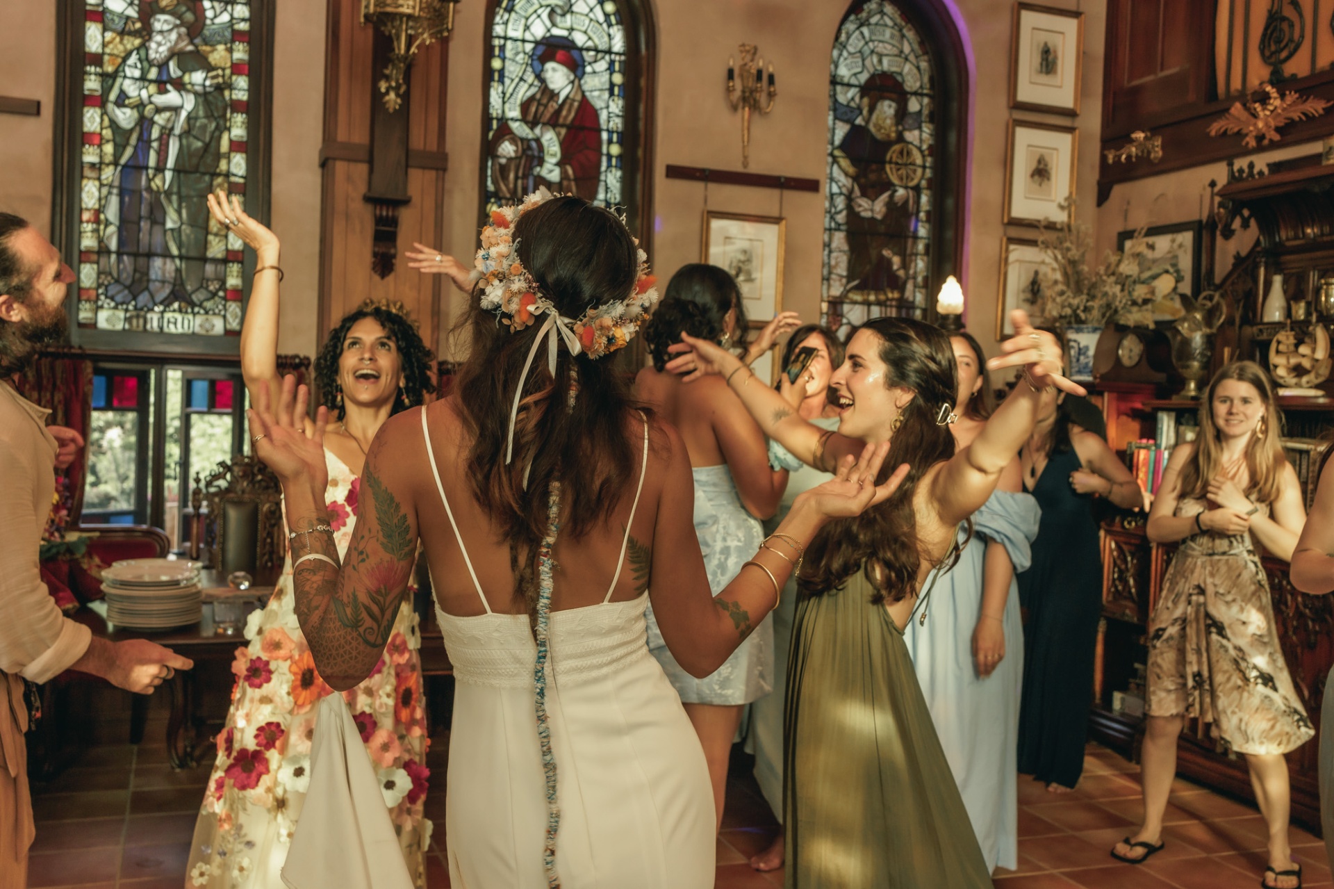 Bride dancing with friends at a wedding reception, arms raised in celebration
